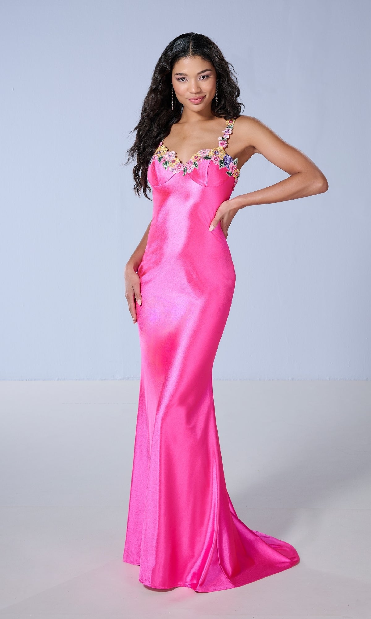 A woman wears the Tiffany 16145 long prom dress, a slim-fit, floor-length satin gown in hot pink with floral embroidery on the straps, standing against a plain light background.